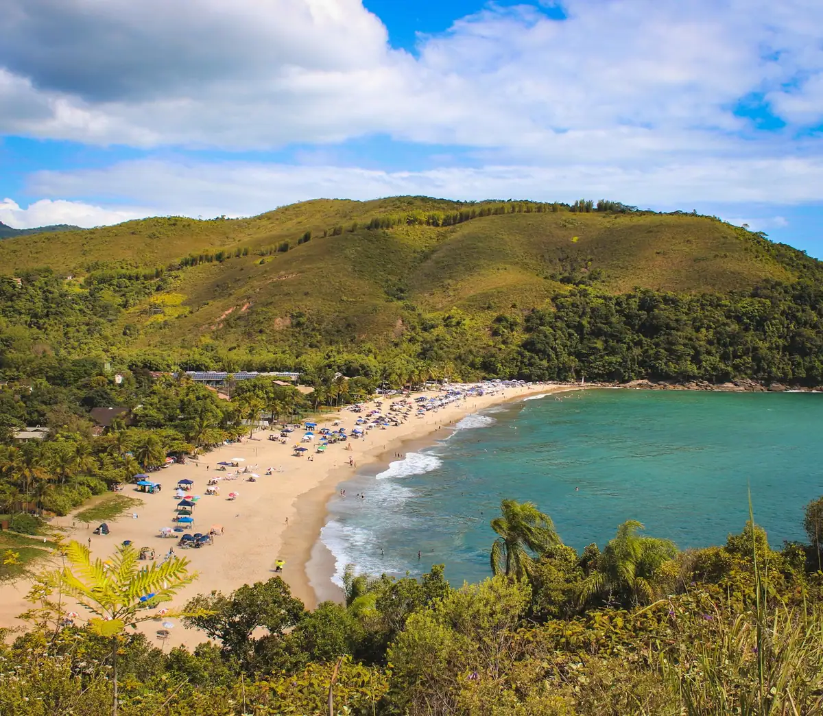 Praia de areia clara cercada de morros cobertos de mata