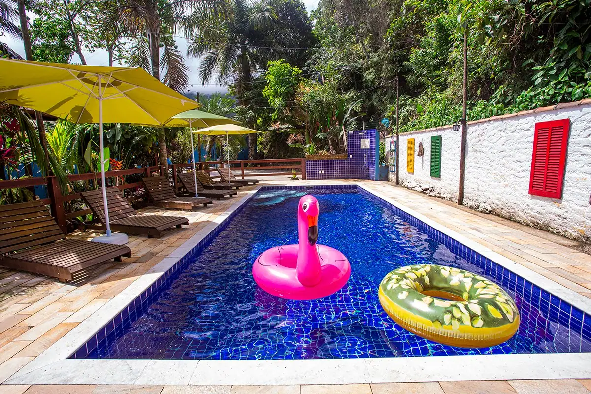 Piscina com boias coloridas, guarda-sóis e jardim