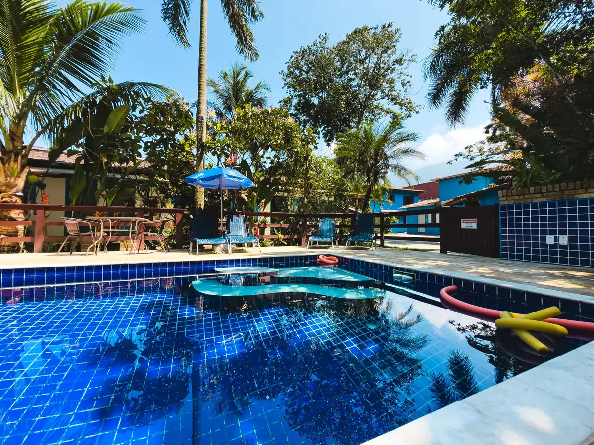 Piscina com palmeiras e guarda-sóis azuis em dia de sol