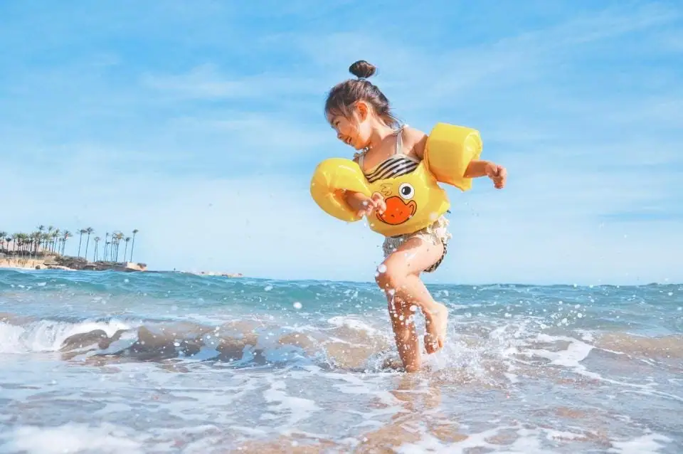 Child playing in the sea with floaties