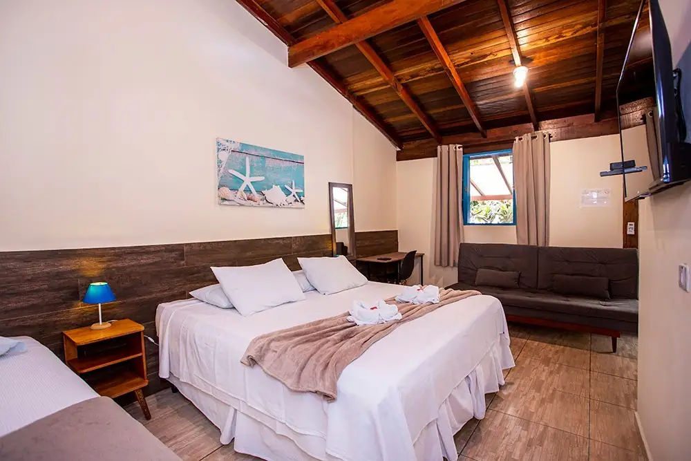 Suíte Deluxe com cama king, sofá e teto de madeira