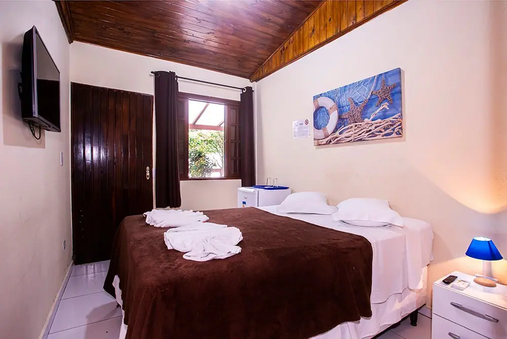 Cama de casal arrumada na Suíte Econômica